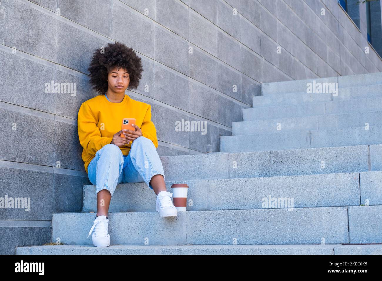 Glückliches Millennial gemischtes Rennen Mädchen in der Straße der Stadt. Positive junge afroamerikanische Frau im Web surfen, Informationen suchen, einkaufen im Online-Shop im Freien Stockfoto