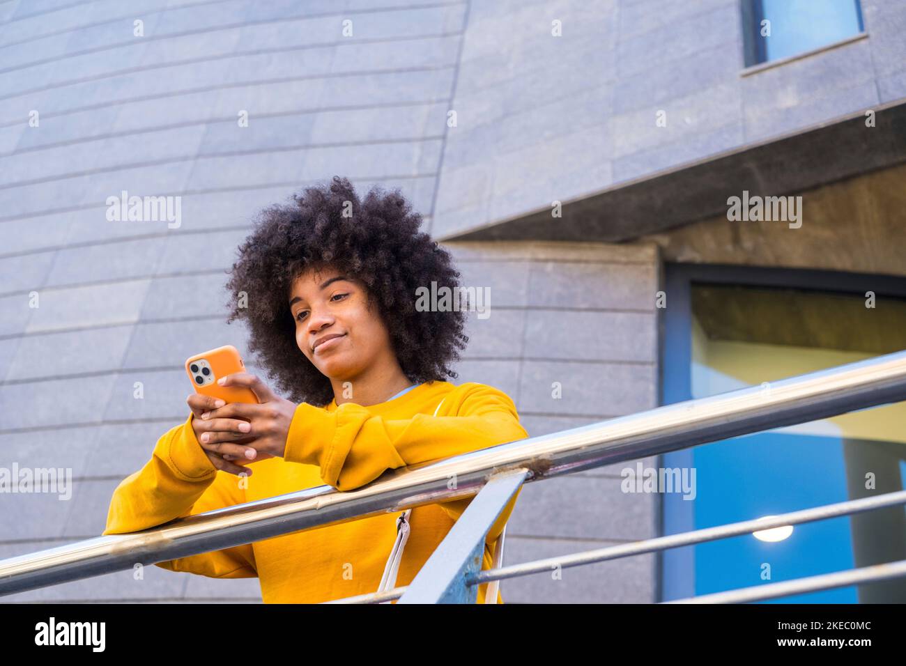 Glückliches Millennial gemischtes Rennen Mädchen in der Straße der Stadt. Positive junge afroamerikanische Frau im Web surfen, Informationen suchen, einkaufen im Online-Shop im Freien Stockfoto