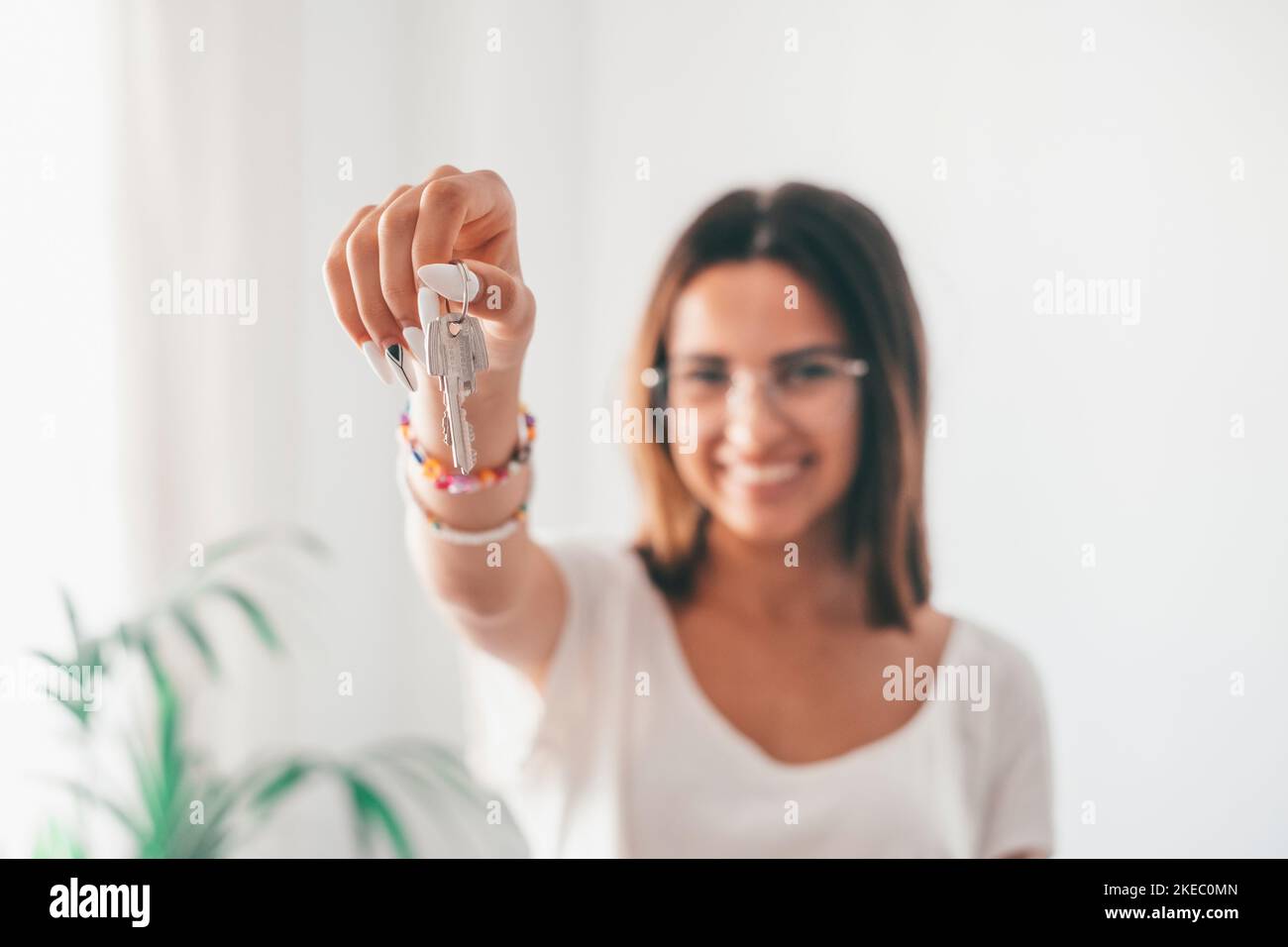 Immobilienmakler mit Schlüsseln für neue Wohnung. Porträt einer attraktiven jungen kaukasischen Frau mit kurzen Haaren und neuen Hausschlüsseln. Junge Hausbesitzerin zeigt Schlüssel. Stockfoto