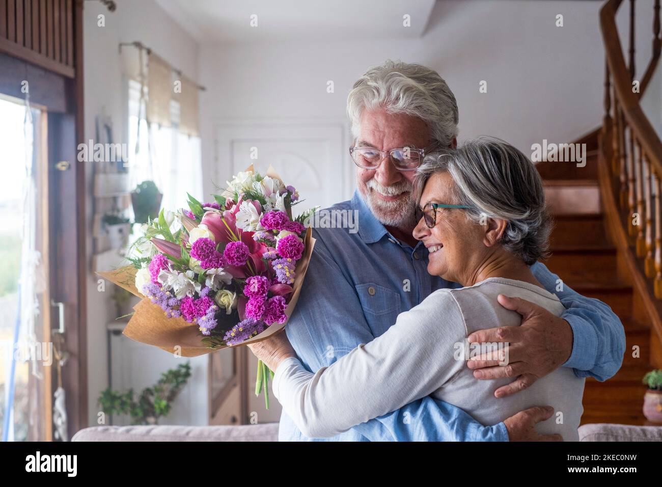Porträt von zwei glücklichen und verliebten Senioren oder reifen und alten Menschen, die Blumen