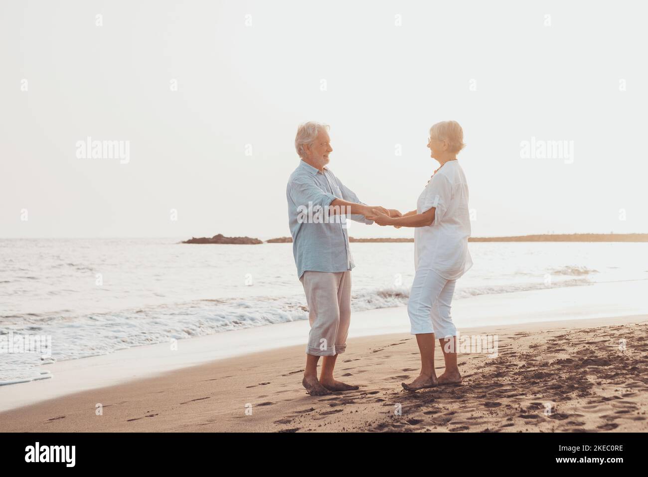 Ein paar ältere Leute, die zusammen tanzen und Spaß am Strand haben und den Moment genießen und leben. Portrait von verliebten Senioren, die sich gegenseitig mit Spaß suchen. Stockfoto