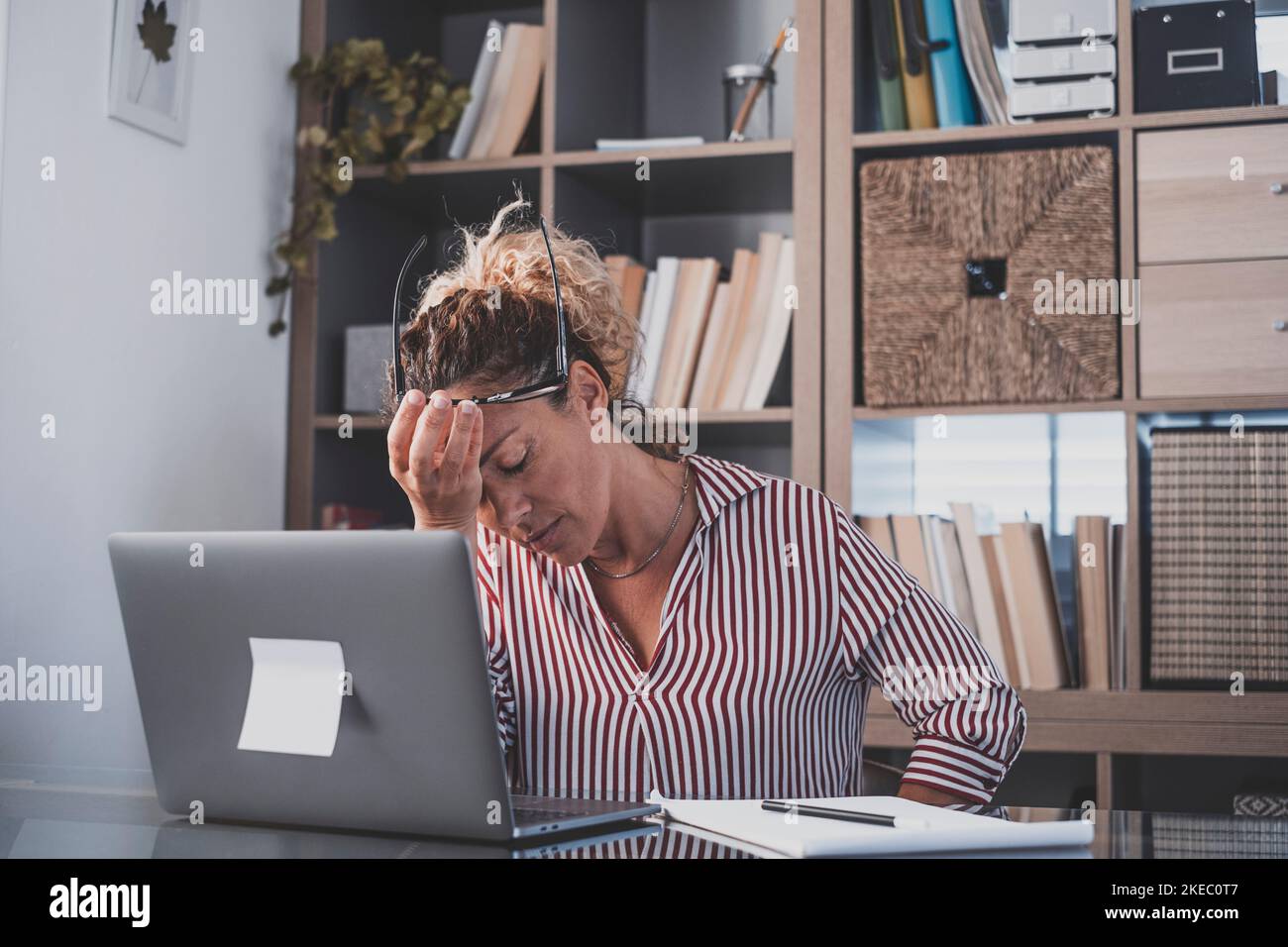 Erschöpfte weibliche Führungskraft, die den Kopf in der Hand hält, fühlt sich nicht energiemotiviert, während sie im Büro am Laptop arbeitet. Verärgert depressive Geschäftsfrau in Panik frustriert durch schlechte Nachrichten online am Computer Stockfoto