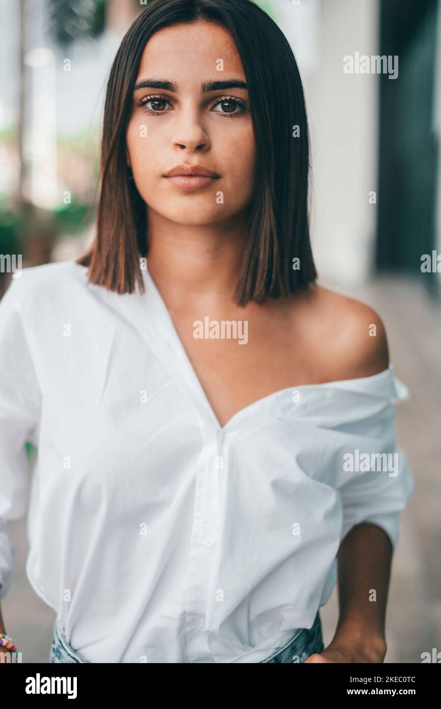 Glückliche junge modische Frau mit kurzen Haaren, die im Freien auf die Kamera schaut. Schöne zufriedene Dame mit kurzen Haaren lächelnd, während sie der Kamera gegenübersteht. Porträt einer selbstbewussten weiblichen Jugend lächelnd Stockfoto