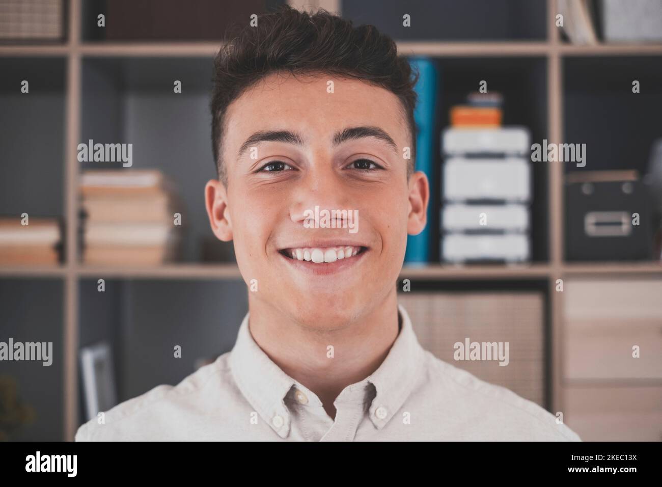 Porträt eines jungen und fröhlichen Mannes, der lächelt und die Kamera anschaut, der Spaß hat. Kopfaufnahme eines Mannes, der zu Hause im Büro arbeitet. Stockfoto