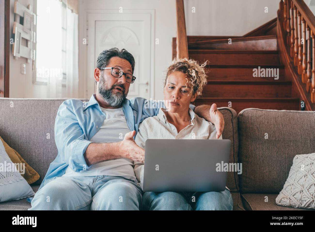 Schockiert kaukasischen Paar Blick auf Laptop-Bildschirm frustriert durch unerwartete schlechte Nachrichten online. Ehemann und Ehefrau enttäuscht und besorgt über den Verlust von Geld in Online-Lotterie, Stockfoto