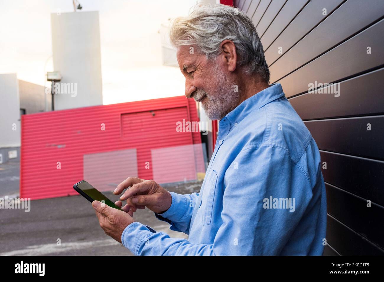 Alter und reifer Mann, der mit ihm im Netz surft Smartphone auf der Straße - älterer Erwachsener, der sein Telefon benutzt Stockfoto
