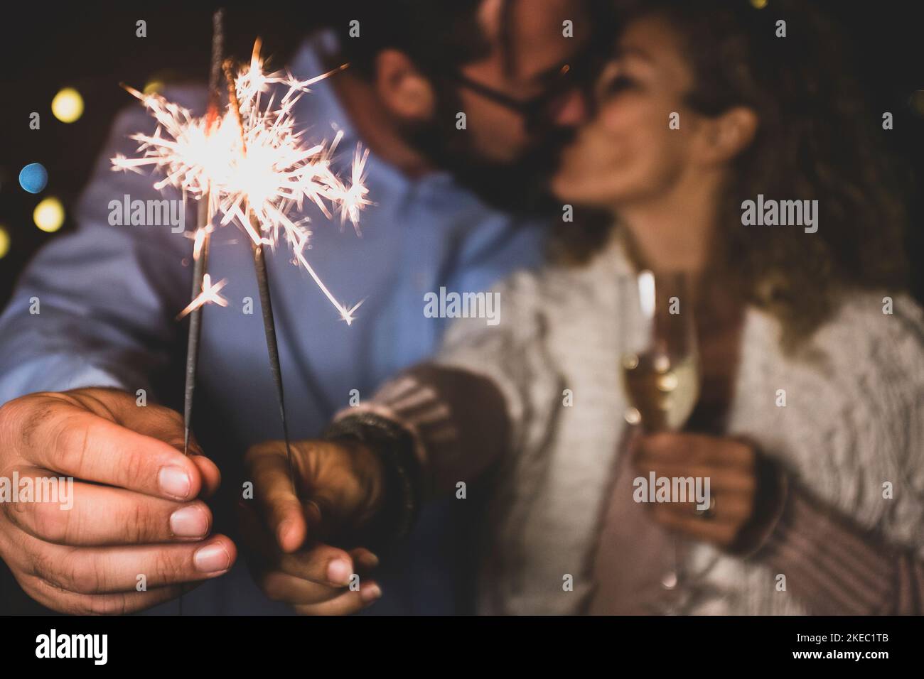 Nettes Paar von zwei Erwachsenen in der Liebe geben einen Verlust zusammen die Neujahr Nacht spielen mit Wunderkerzen in der Hand in der Nähe der Kamera küssen sich gegenseitig Stockfoto