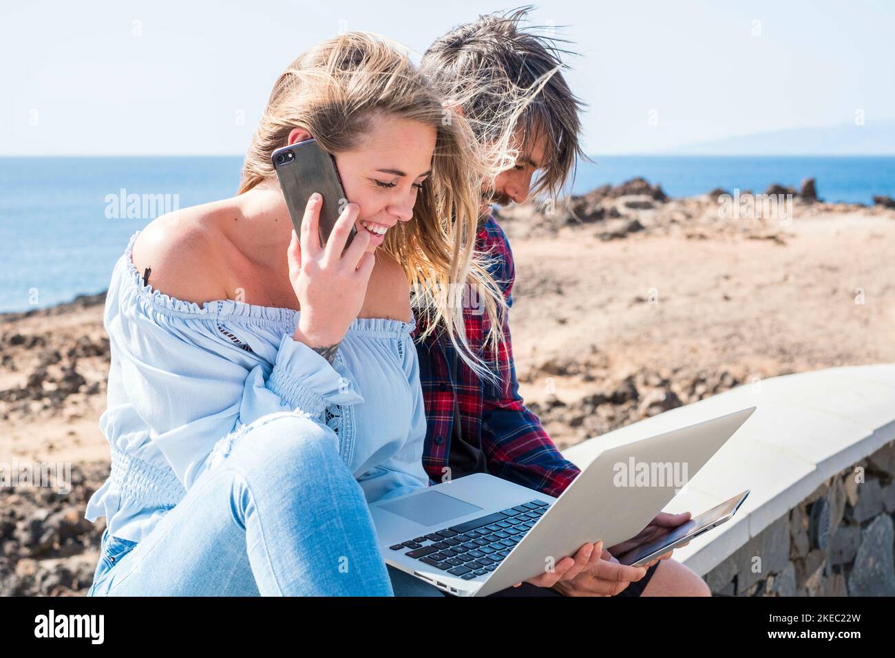 Happy modern schönes Paar genießen Technologie im Freien zusammen in Freundschaft Oder Beziehung - junge Menschen mit Laptop und Telefon interniert Verbunden - Ozean im Hintergrund Stockfoto