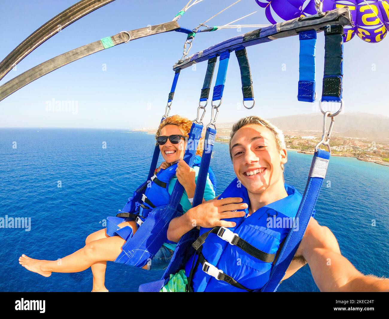 Nahaufnahme und Selfie von zwei glücklichen Menschen, die zusammen fliegen Mit einem Drachen in der Mitte des Meeres haben Spaß - ein paar Erwachsene genießen den Sommer Stockfoto