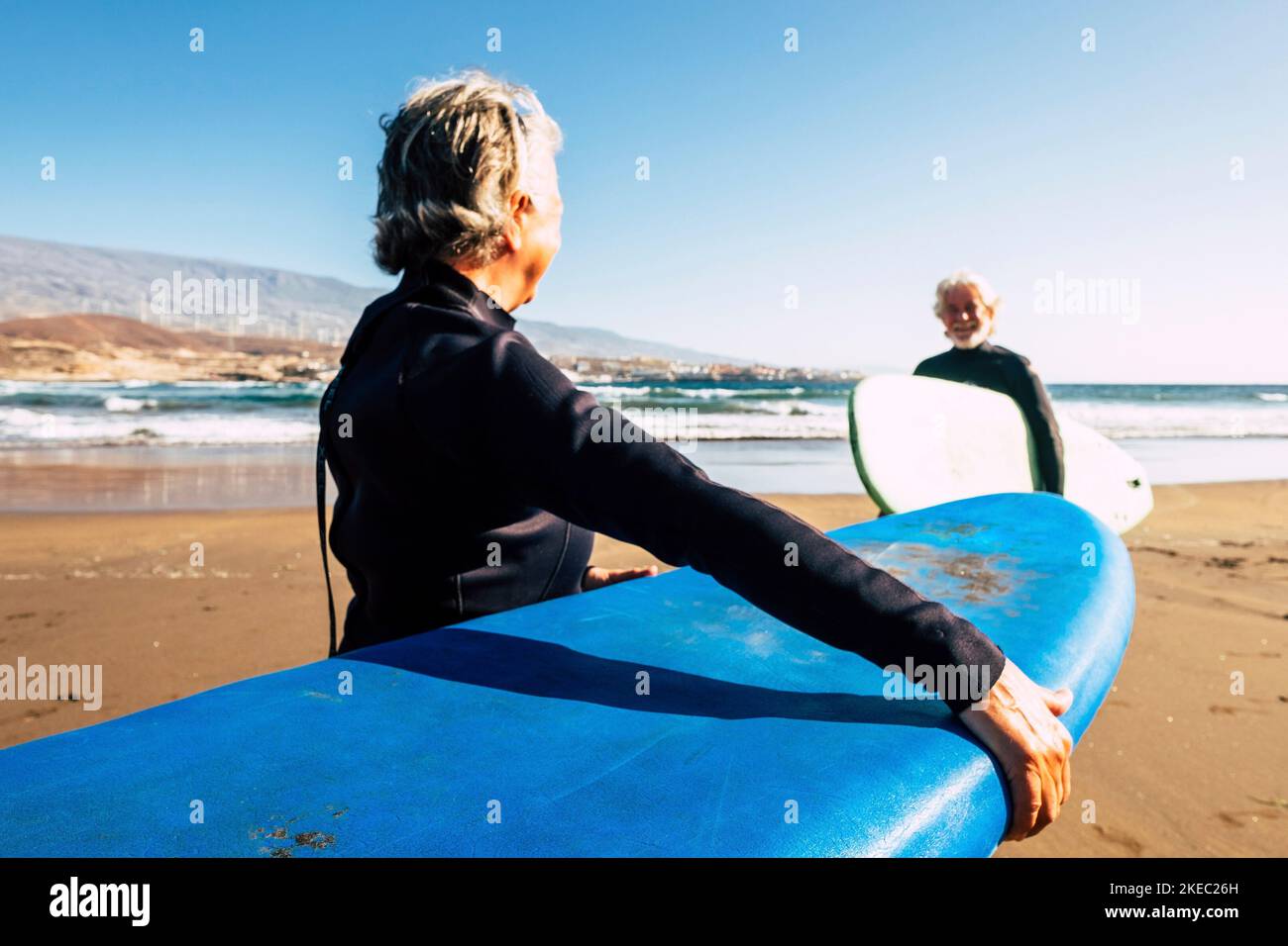 Zwei alte und reife Menschen genießen ihren Urlaub im Freien am Strand und haben Spaß zusammen mit Neoprenanzügen und Surfbrettern bereit zum Surfen - aktiver Senior, der im Sommer Wassersport macht Stockfoto