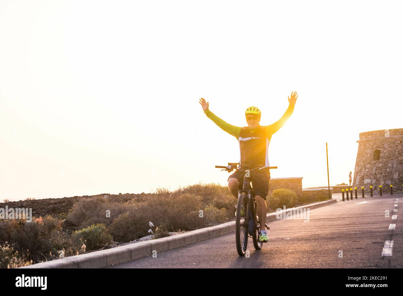 Ein älterer oder Rentner, der alleine mit seinem Fahrrad Spaß hat Mit Armen und Händen nach oben - Fitness und gesunder Lebensstil - aktiver reifer Mann macht Übung Stockfoto