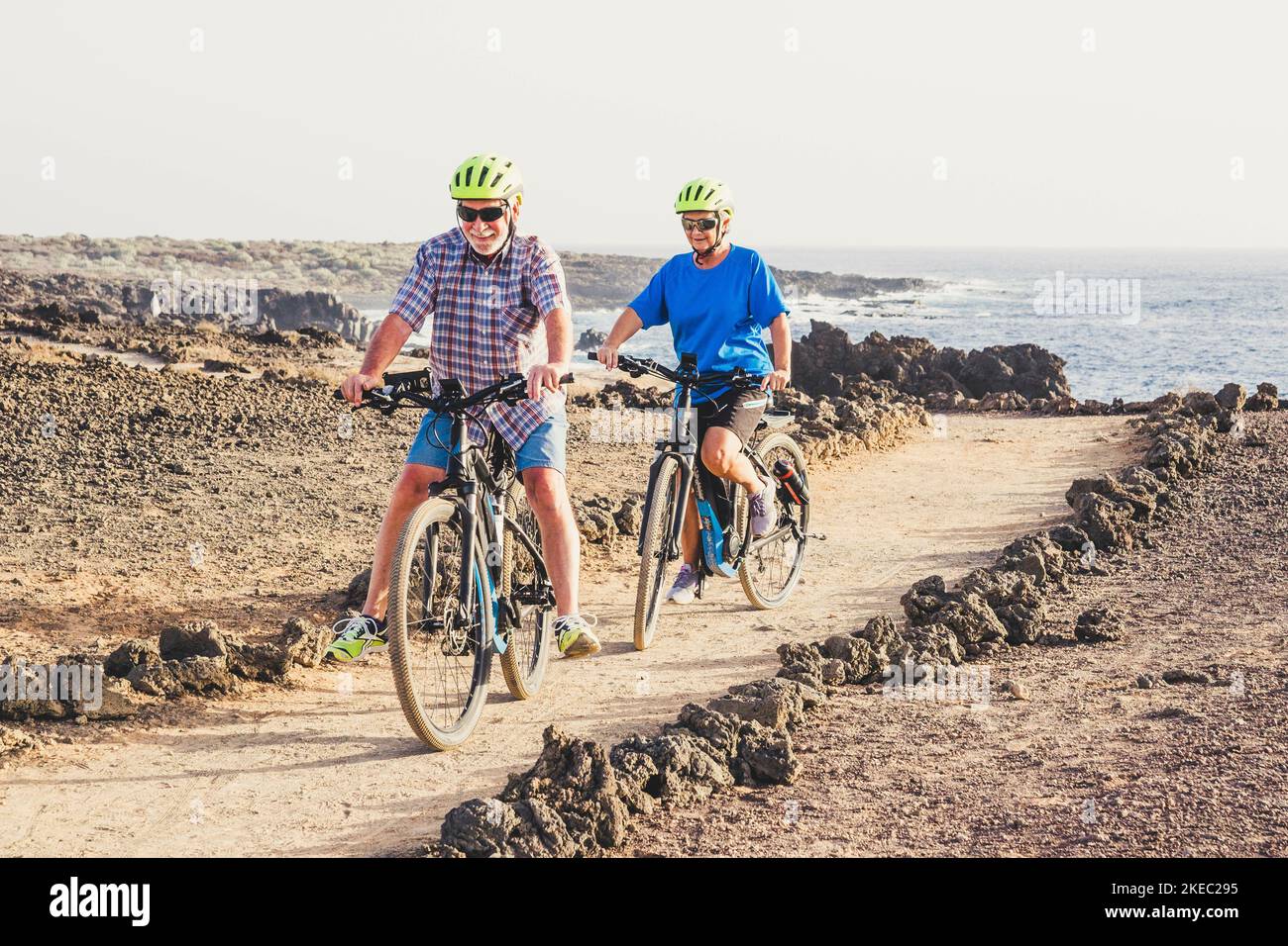 Ein paar von zwei Senioren, die zusammen auf dem Boden Fahrrad fahren, Spaß haben - Bewegung machen, um gesund und fit zu sein Stockfoto