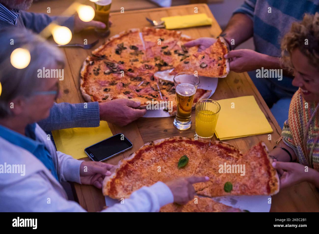 Eine Gruppe von vier Personen, die zusammen Pizza essen und Bier trinken In der Nacht zu Hause oder in einem Restaurant - Familie Gemeinsam etwas feiern Stockfoto