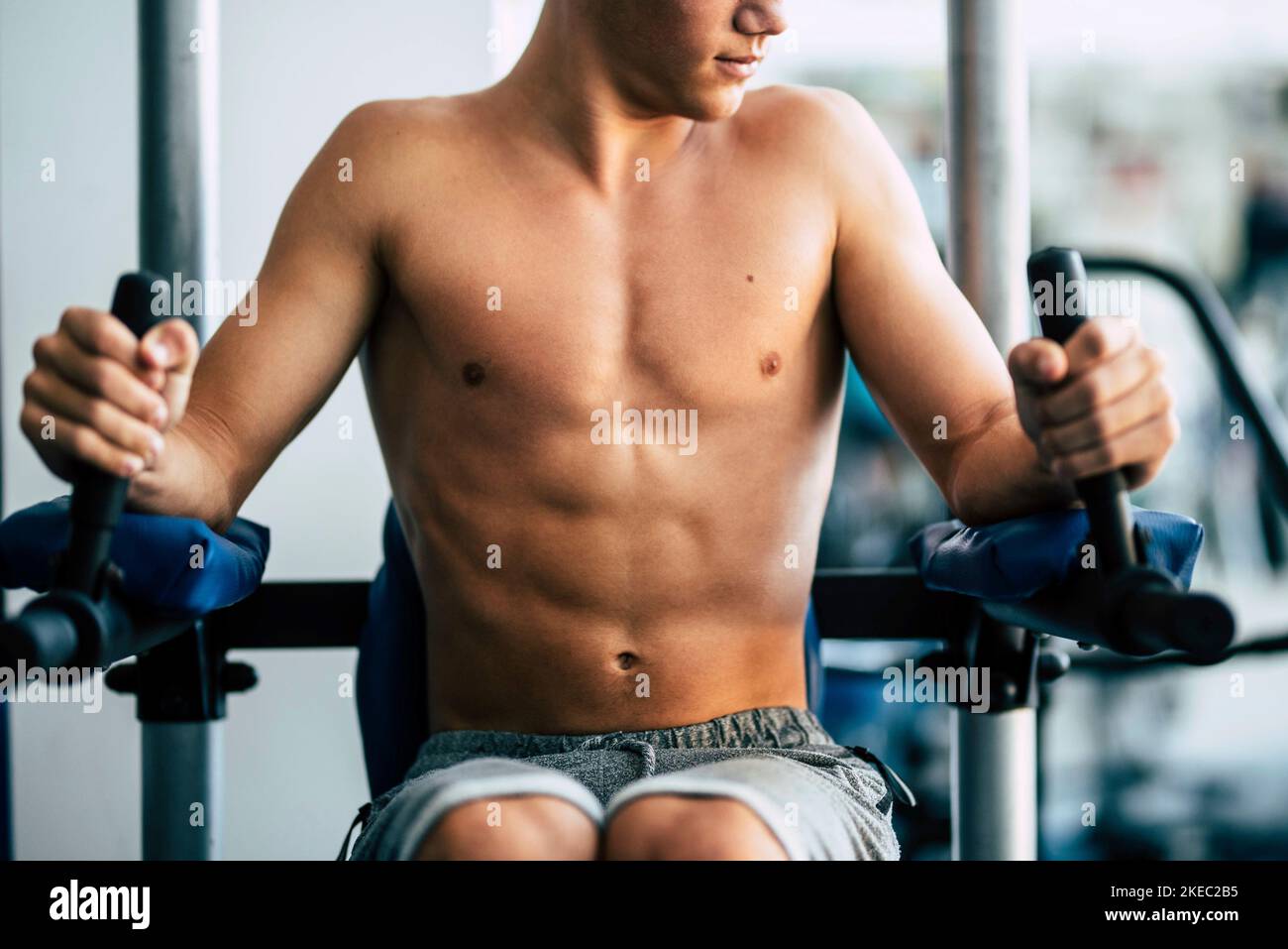 Nahaufnahme des Mannes tun Übung im Fitnessstudio ohne t-Shirt zeigt seine Bauchmuskeln - aktiver Teenager baut seinen Körper Allein Stockfoto