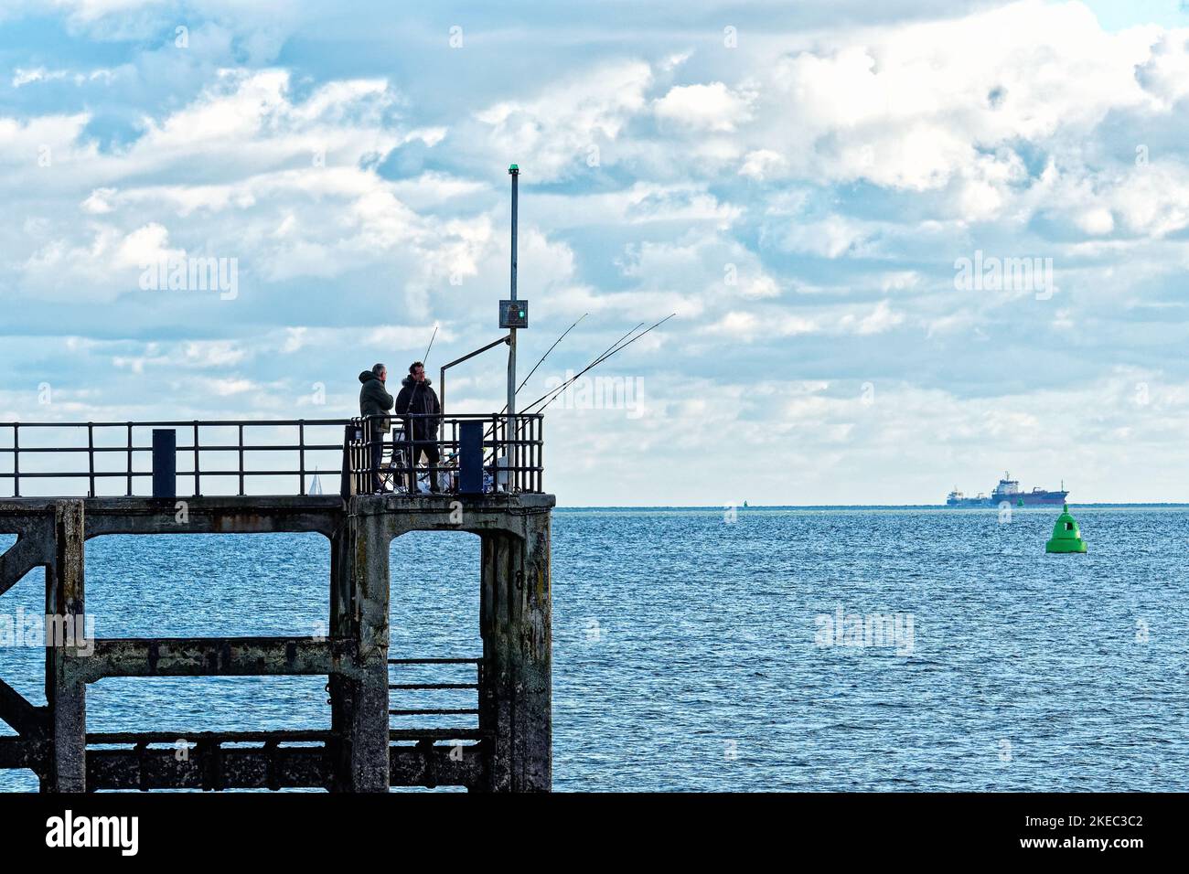 Zwei Männer Seefischen mit Ruten von einem Steg in altem Portsmouth mit Spithead am Horizont Hampshire England Großbritannien Stockfoto