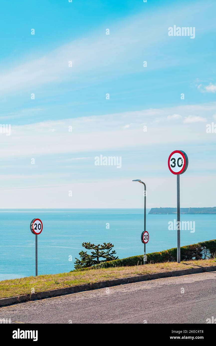 Straßenverkehrsgeschwindigkeitsschilder auf einer Straße am Meer an einem hellen Sommertag. 20MPH und 30mph Zahlen auf einem weißen Kreis mit einem roten Rand. Stockfoto