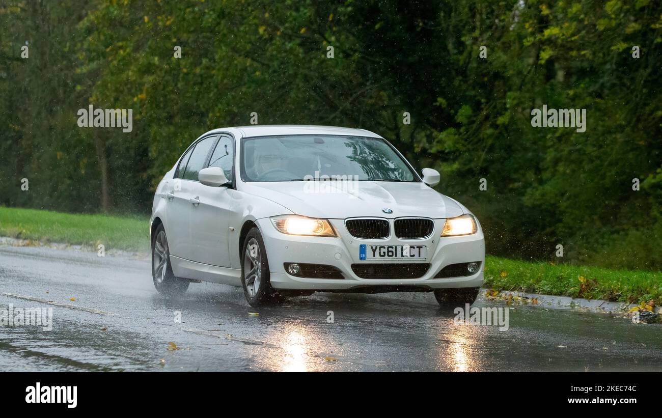 Weißer 2011-Dieselmotor der BMW 3-Serie bei Regen auf nasser Straße Stockfoto