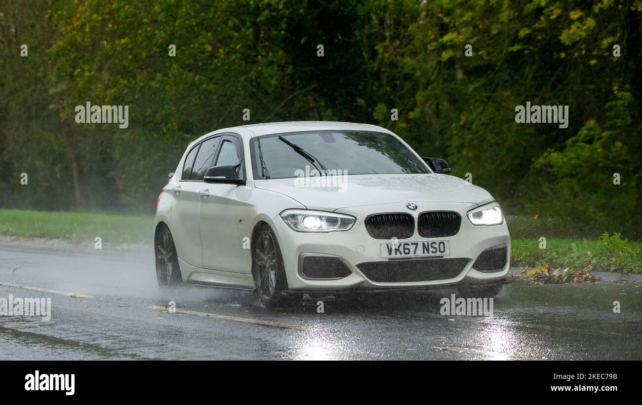 2017 weißer BMW der Serie 1 fährt im Regen auf nasser Straße Stockfoto