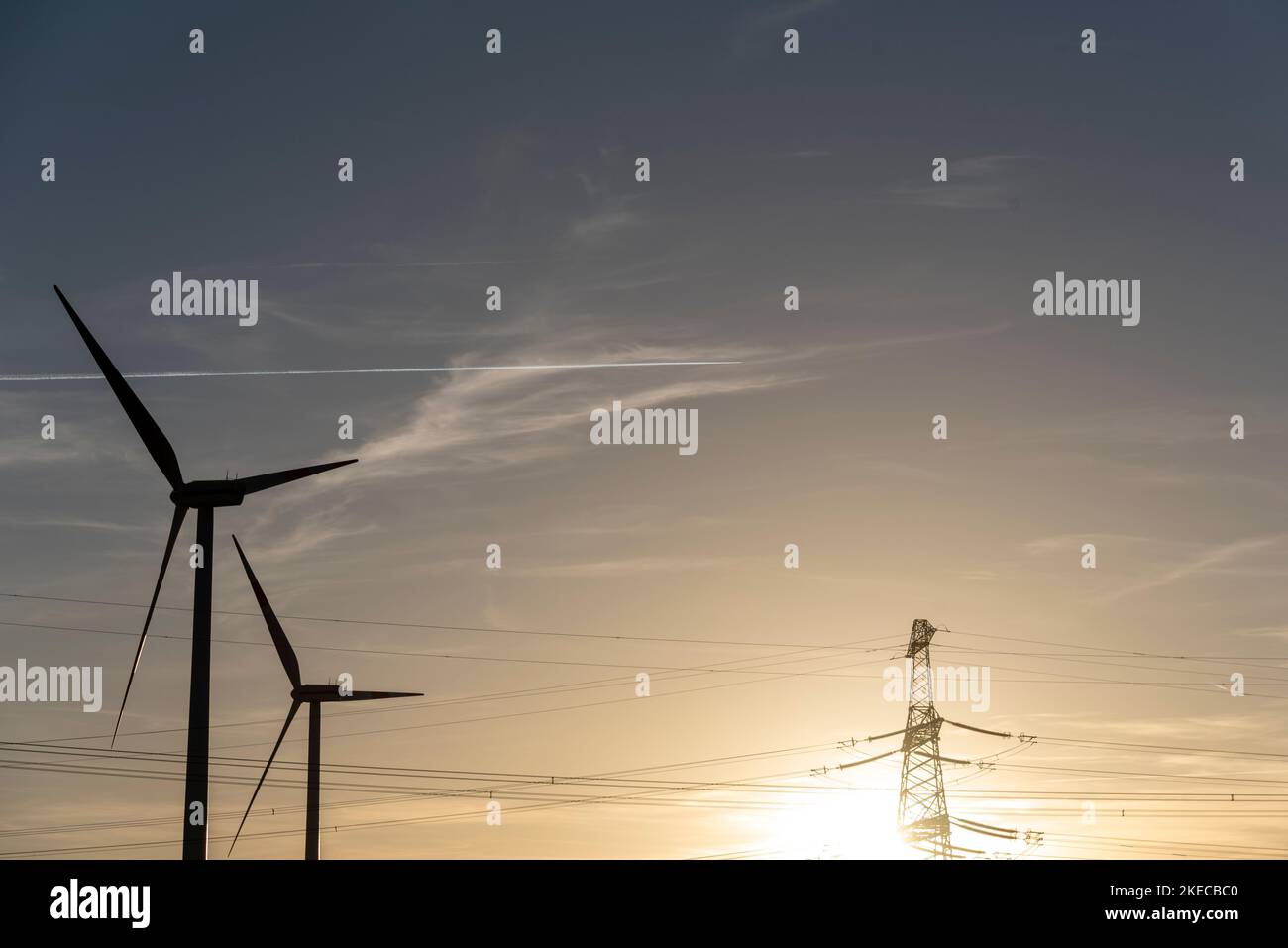 Zwei Windturbinen stehen neben einem Strommast. Stockfoto