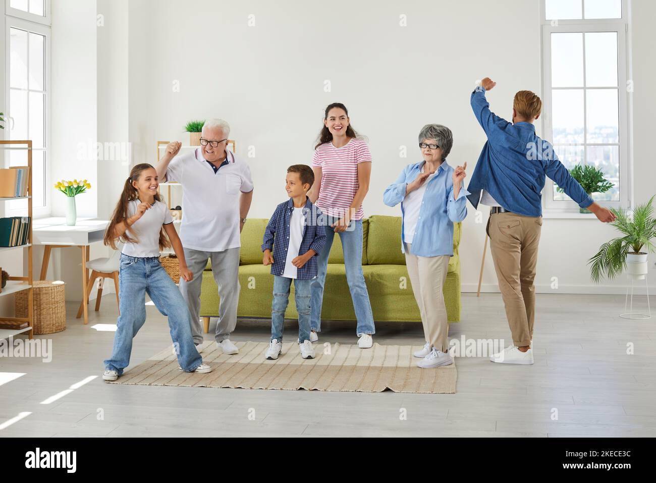 Fröhliche, fröhliche, lustige Familie, die im Wohnzimmer ihres Hauses oder ihrer Wohnung tanzt Stockfoto