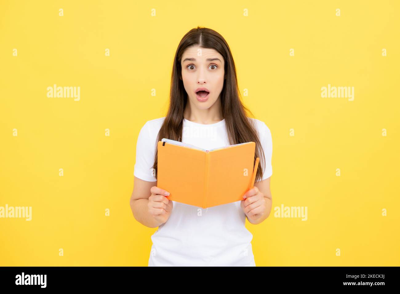 Teenager Student Mädchen auf gelbem Hintergrund isoliert. Fröhliche junge Frau Student im Hemd halten Notizbücher zeigen. High School University College Stockfoto