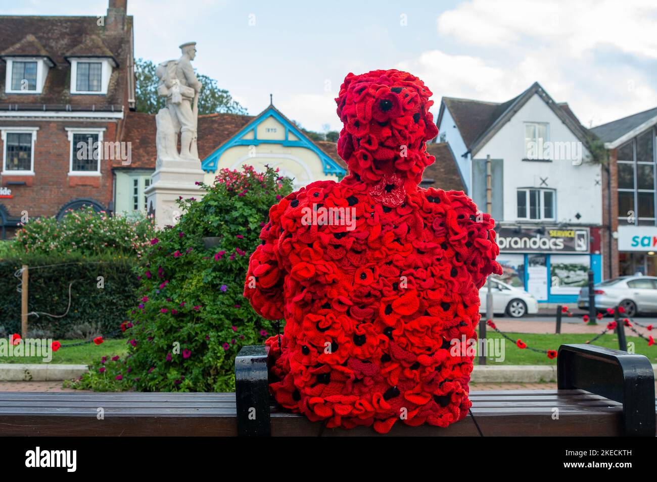 Chesham, Buckinghamshire. VEREINIGTES KÖNIGREICH. 11. November 2022. Eine auffällige Figur zum Gedenktag, in der ein Mann mit roten Mohnblumen auf einem Sitz in Chensham neben dem Kriegsdenkmal sitzt und eine weiße Taube in der Hand hält. Quelle: Maureen McLean/Alamy Live News Stockfoto