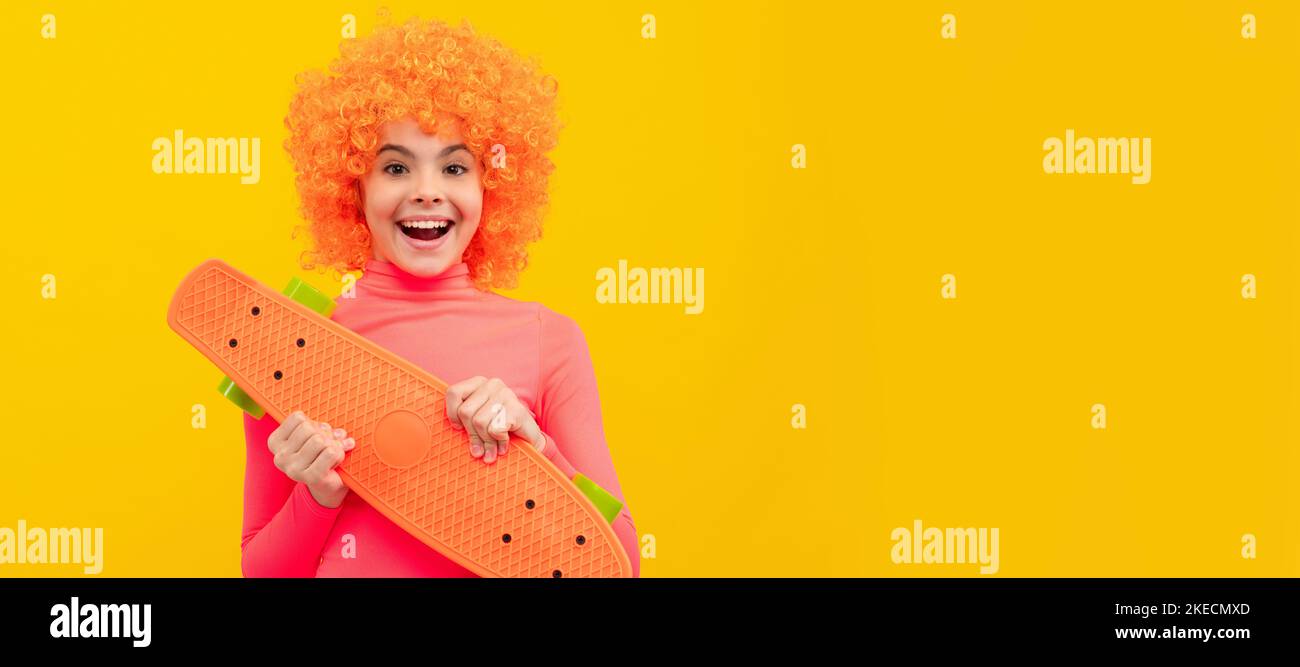 Happy cool Mädchen mit orangefarbenen Haaren in rosa Poloneck Lächeln hält Pennyboard, Skateboard. Lustige Teenager Kind auf der Party, Poster-Banner-Header mit Kopie Stockfoto