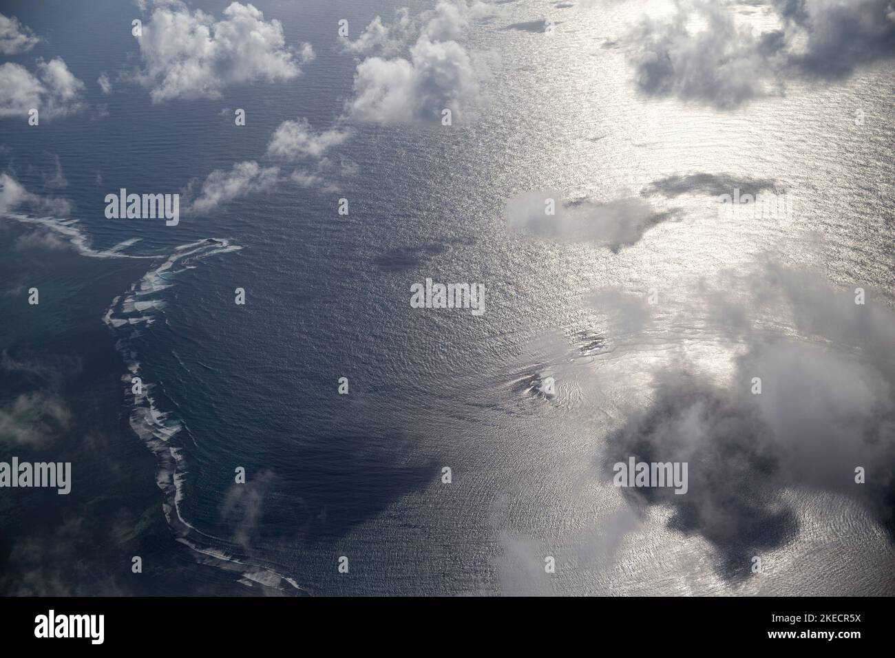 Wunderschöne Landschaft durch das Fenster des Flugzeugs. Weiche, flauschige Wolken schweben und viele hellblau-grüne Inseln sind um das Meer verstreut. Weiches blaugrün und verschwommener Hintergrund. Stockfoto