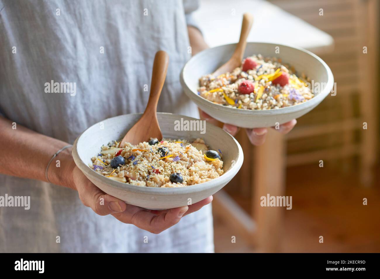 ayurvedische Küche, Frau hält zwei leichte Tonschüsseln mit Grießbrei und Früchten in den Händen Stockfoto