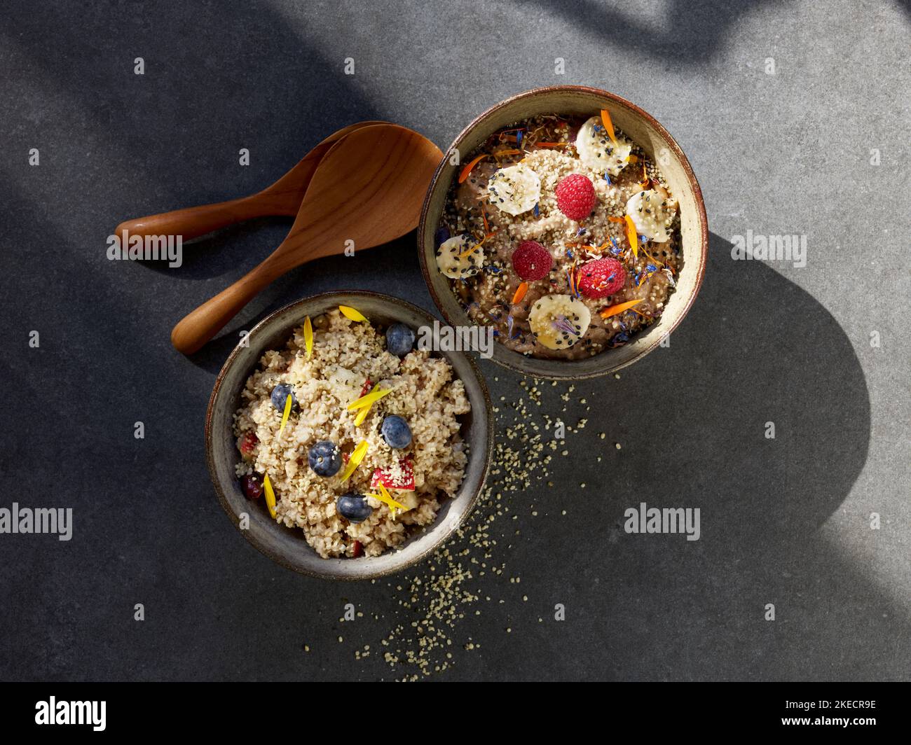 ayurvedische Küche, zwei Tonschüsseln mit Grießbrei und Früchten auf einem dunklen Steinteller Stockfoto