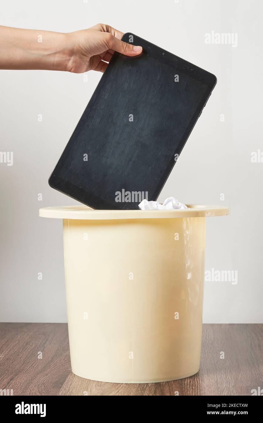 Jemand, der ein ipad mit offenem Deckel in einen Papierkorb hält, um zu zeigen, wie es in Gebrauch ist Stockfoto
