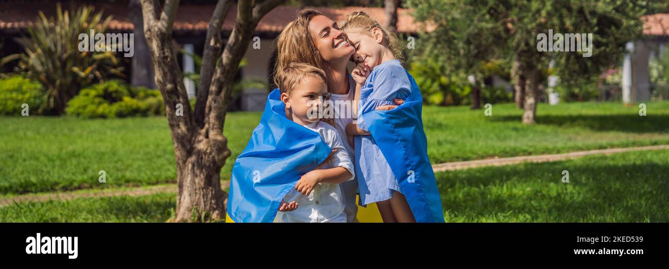 BANNER, LANG FORMAT ukrainische Mutter mit zwei Kindern mit Flagge der Ukraine. Draußen. Konzept des Problems des Krieges in Europa, Unterstützung von Familien und Stockfoto
