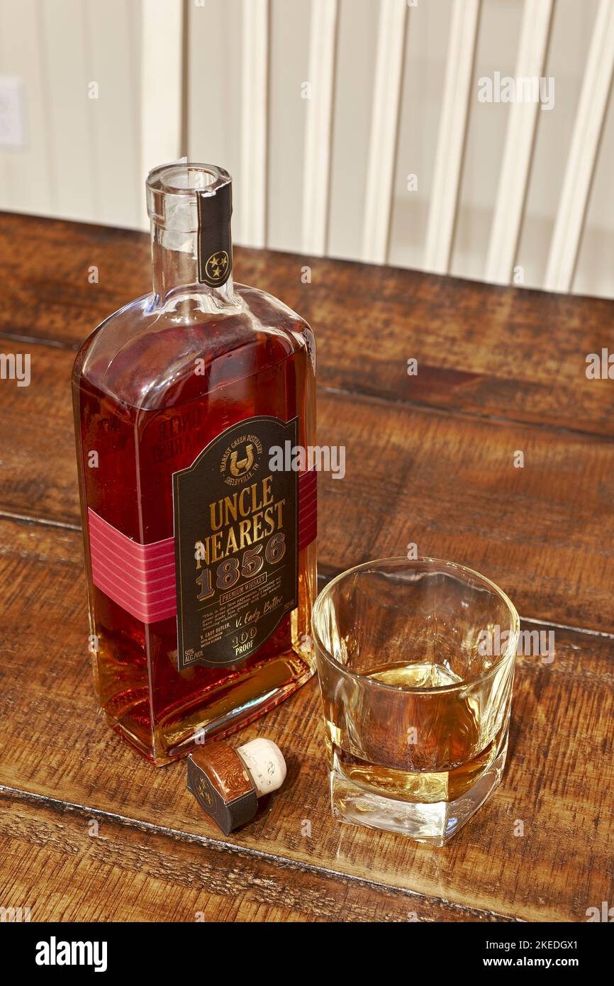 Onkel, das nächste, oberste Regal Tennessee Bourbon Whisky Flasche neben einem Glas Bourbon, ordentlich oder ohne Eis auf einem Tisch. Stockfoto