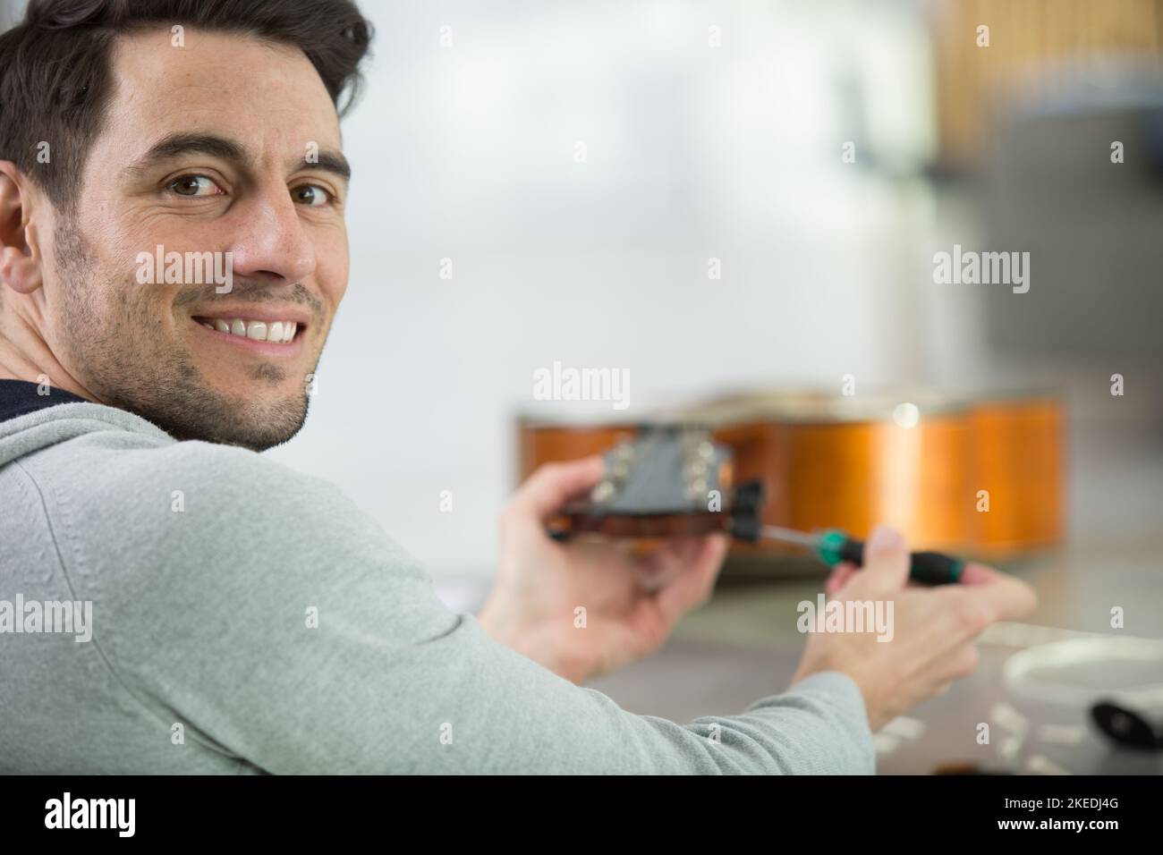 Junge gut aussehende Werkstatt Reparatur Gitarre Stockfoto