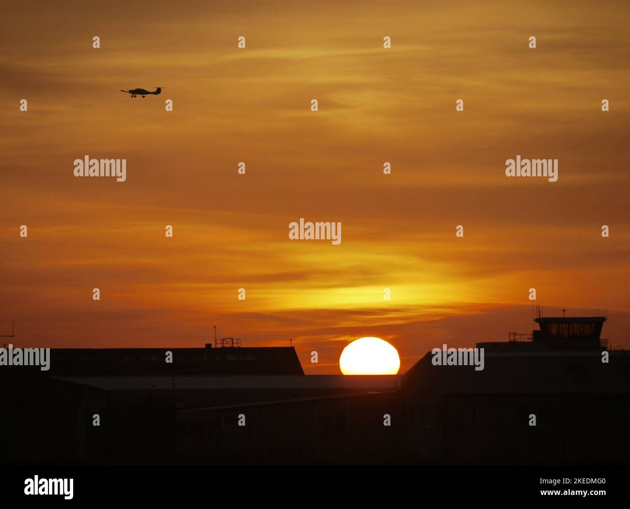 Ein leichtes Flugzeug im Flug, das bei Sonnenuntergang über dem Brighton City Airport, Shoreham-by-Sea, Großbritannien, silhouettiert wurde. Ricardo-Logo sichtbar. Stockfoto