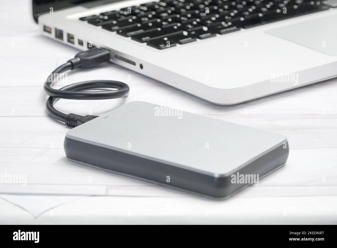 Im Büro, Laptop auf dem Tisch verbunden USB-Kabel mit externer Festplatte Stockfoto