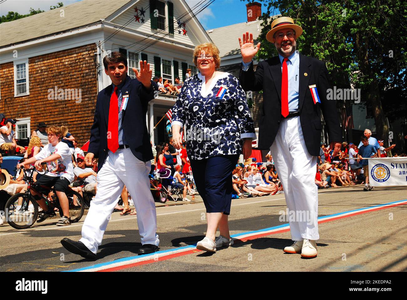 Ein Bürgermeister der Kleinstadt und die Mitarbeiter marschieren und winken am 4. Juli in Bristol Rhode Island, der ältesten Parade zum Unabhängigkeitstag in den USA, vor der Menge Stockfoto