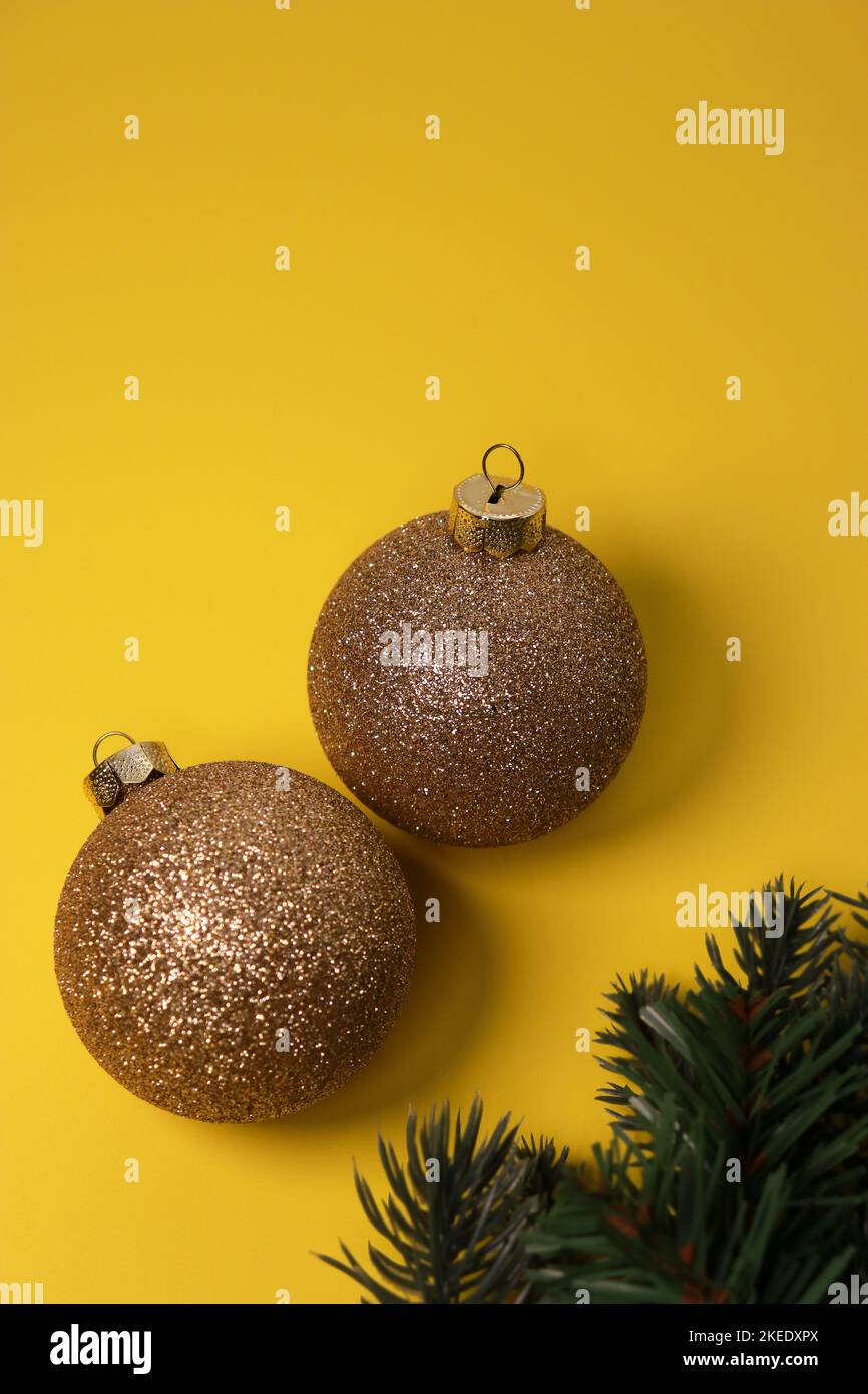 goldene Weihnachtskugeln auf gelbem Hintergrund mit grüner Kiefer Stockfoto