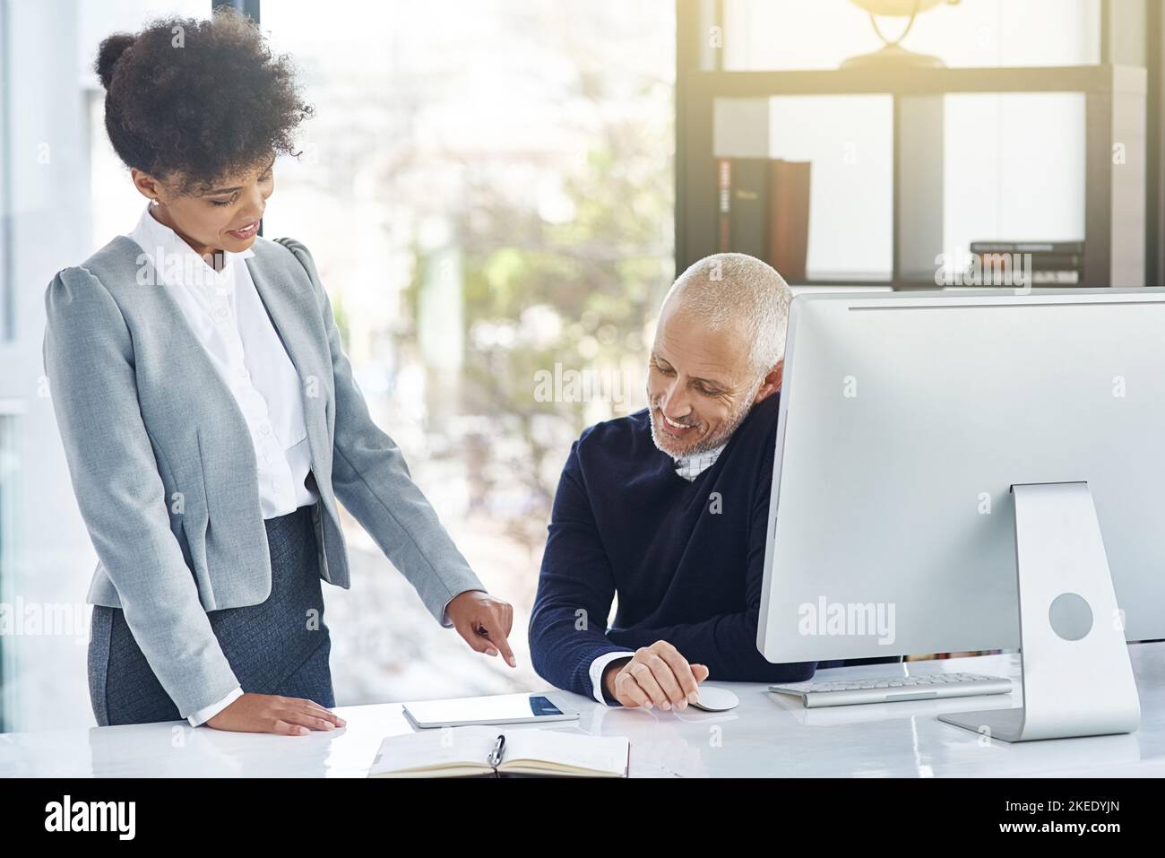 Sie sind nie zu alt, um von Ihren Mitarbeitern zu lernen. Eine junge Geschäftsfrau zeigt ihrem Kollegen etwas auf einem Tablet. Stockfoto