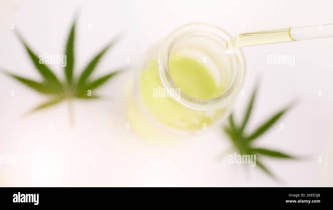 Cannabis, Unkraut und cbd-Öl in einem Glas für Depressionen, Stress und Angst mit legalen Marihuanablättern oder Blumen auf einem Tisch. Dreippig, 420 ODER entspannend Stockfoto