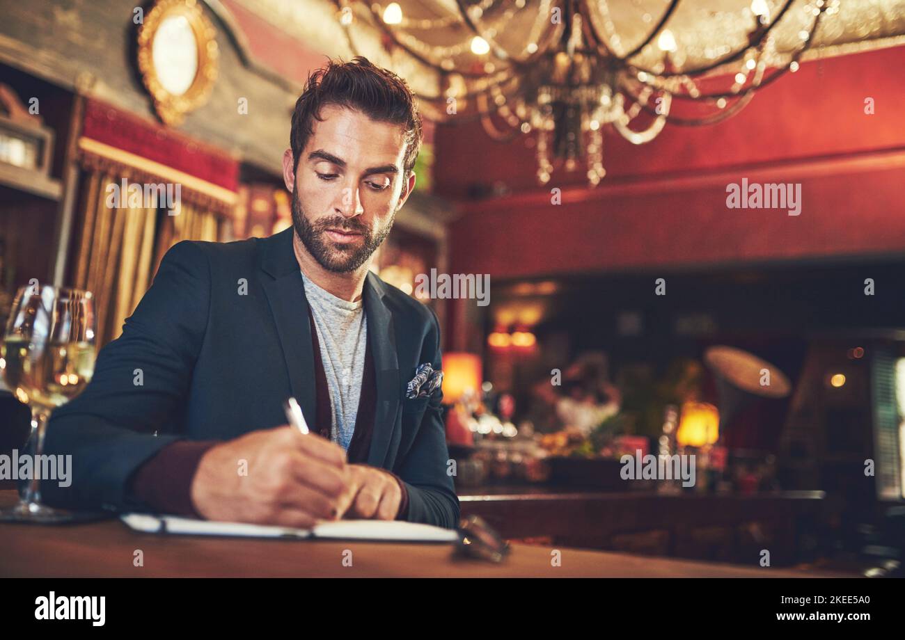Arbeiten an seiner Einführung. Ein junger Mann, der mit seinem Tagebuch in einer Bar sitzt. Stockfoto