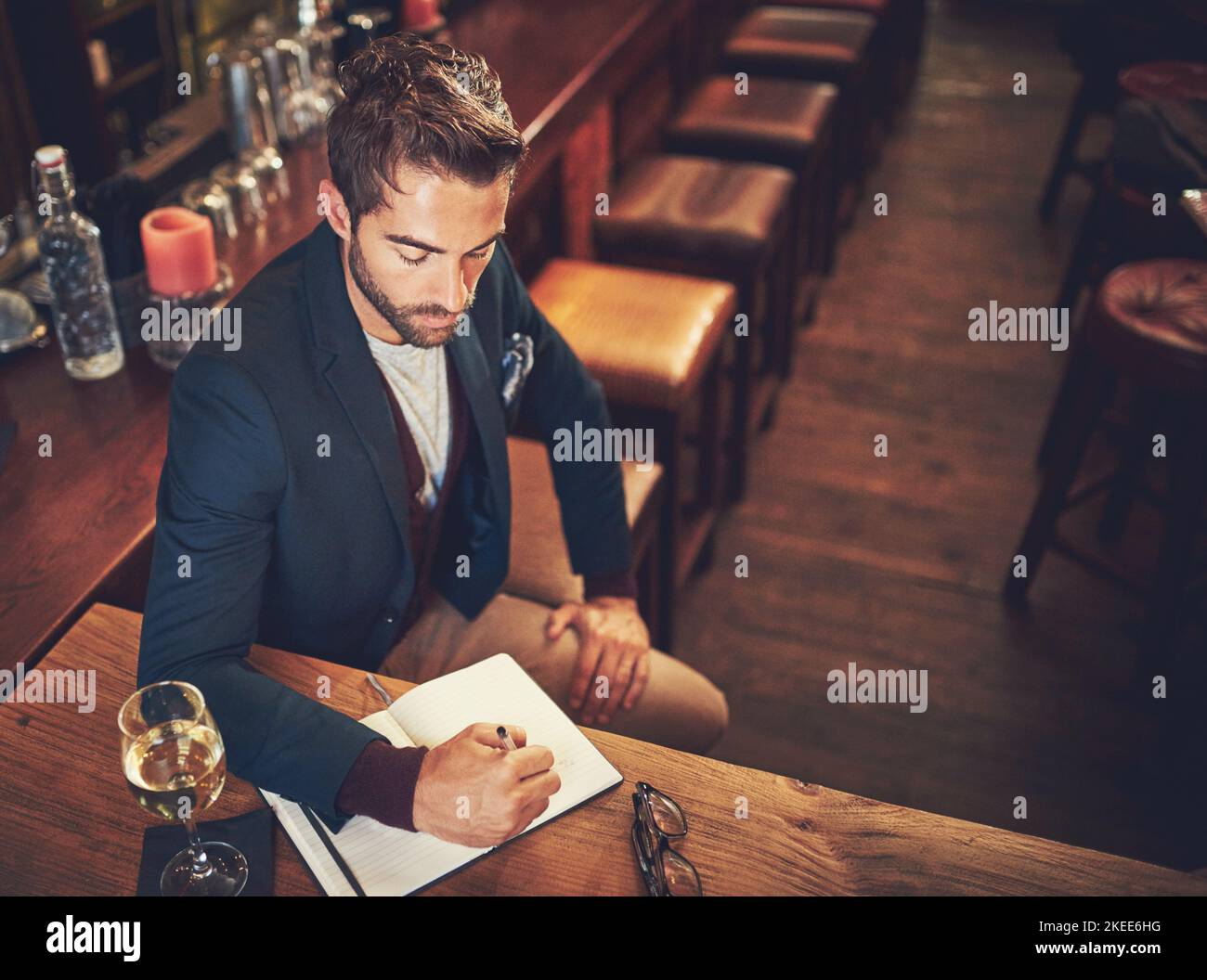 Einige Ideen niederzudrücken. Aufnahme eines jungen Mannes, der mit seinem Tagebuch in einer Bar sitzt. Stockfoto