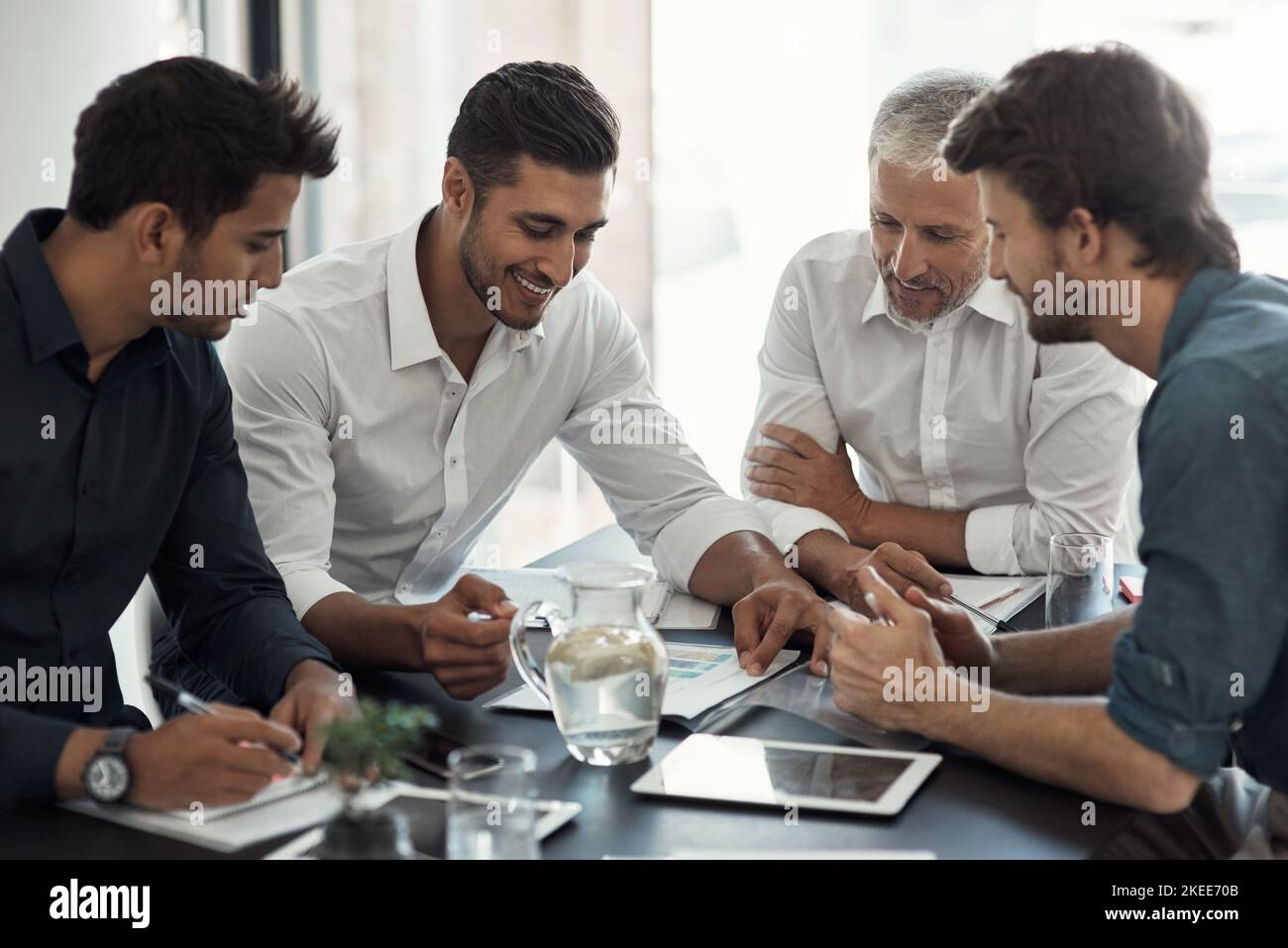 Diese Jungs kennen ihr Geschäft. Eine Gruppe von Geschäftsleuten, die ein Treffen um einen Tisch in einem Büro haben. Stockfoto