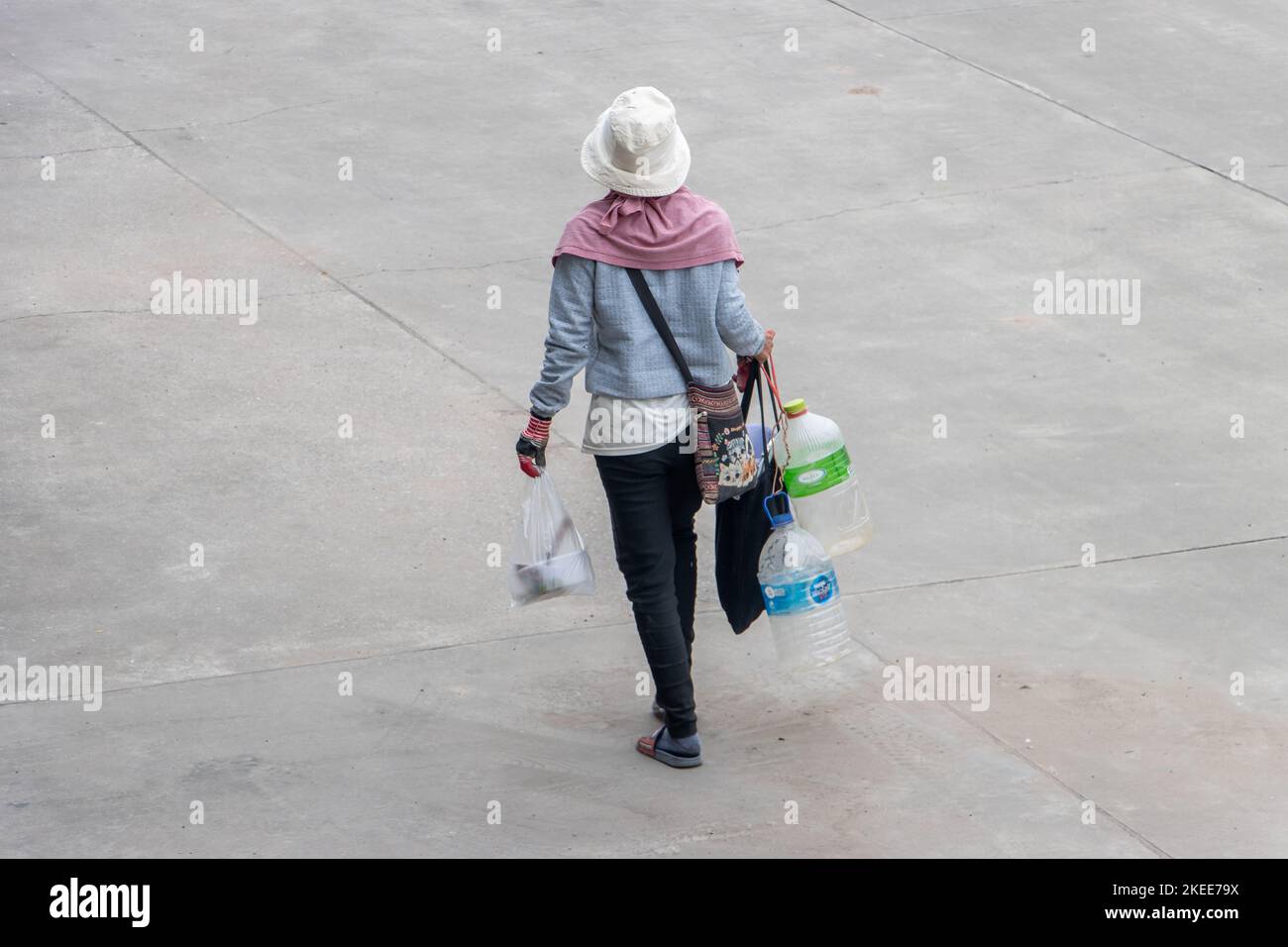 SAMUT PRAKAN, THAILAND, SEP 28 2022, Eine Arbeiterin trägt leere Plastikwasserflaschen entlang der Straße Stockfoto