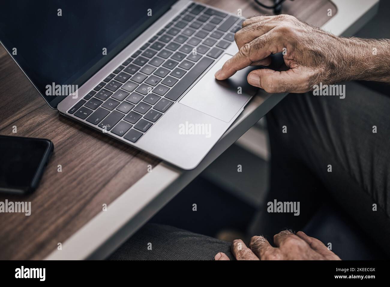 Nahaufnahme des männlichen Senior-Profis beim Scrollen auf dem Laptop am Tisch. Geschäftsmann arbeitet in der U-Bahn oder im Intercity-Zug. Er verwendet Wireless Stockfoto