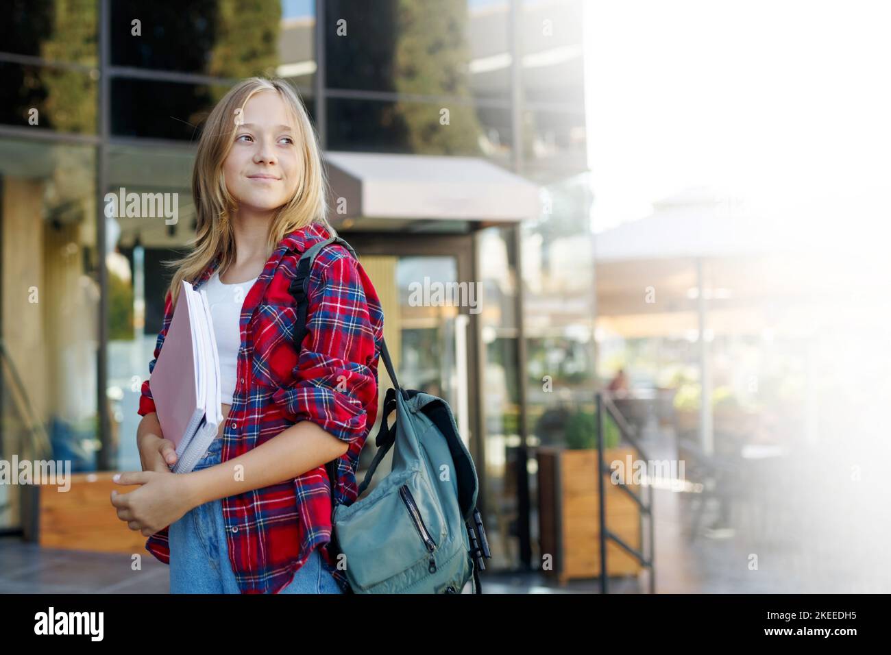 Niedliche 13 Jahre Mädchen Student Teenager mit einem Rucksack hält Notizblöcke und Notizbücher auf der Straße Stockfoto