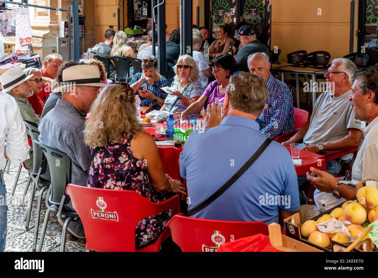 Eine Gruppe von Touristen/Besuchern, die sich mit Snacks an Einem Tisch im Capo Markt (Mercado del Capo), Palermo, Sizilien, Italien, absetzen. Stockfoto