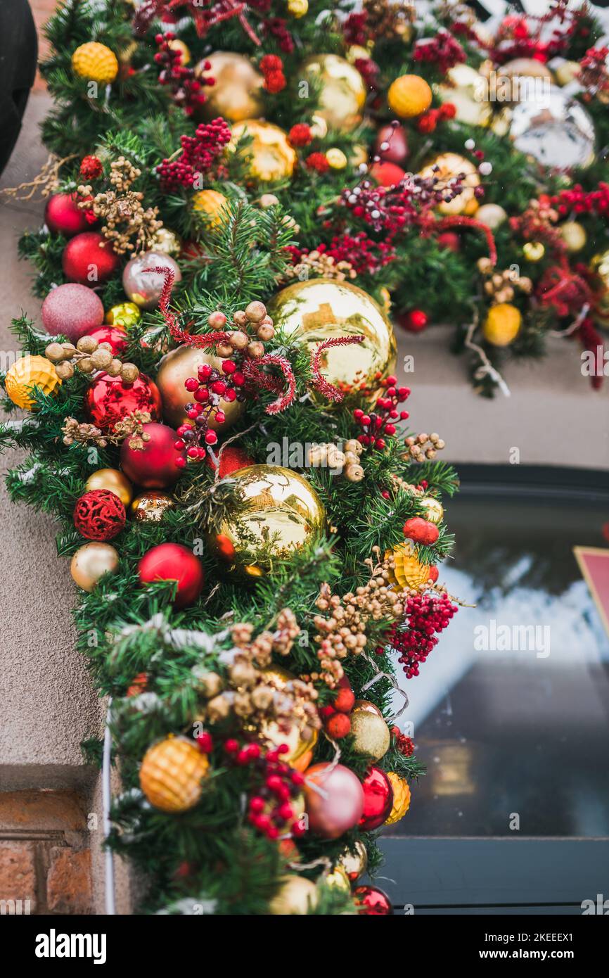 Stilvolle tannenzweige mit roten und goldenen Kugeln vor dem Gebäude auf dem Weihnachtsmarkt in der Stadtstraße. Straßendekor im Winter Stockfoto