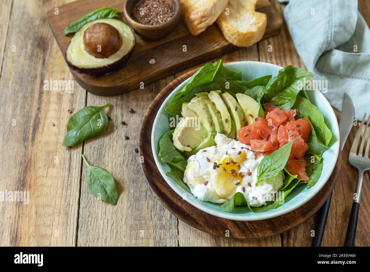 Ketogene, Keto- oder Paläodiät. Köstliches Frühstück oder eine Schüssel mit gesalzenem Lachsfisch, Avocado, gekochtem Ei und Spinat auf einem rustikalen Tisch. Kopieren Sie den SPAC Stockfoto