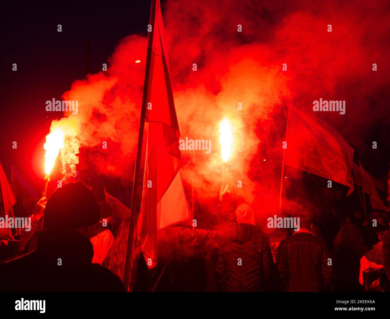 Menschen mit Fackeln und Fahnen während des Unabhängigkeitstages. Polen, 11. November 2022. unabhängigkeitsmarsch. Abend, helle Flammen von Fackeln, Rauch. Stockfoto